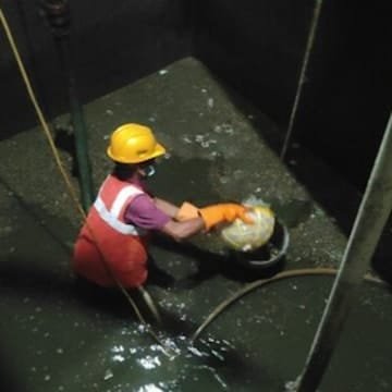 Technician removing sludge and sediment from a water tank